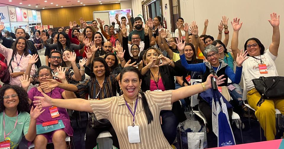 Plateia acenando para a câmera, com Carol Villaça de braços abertos na frente
